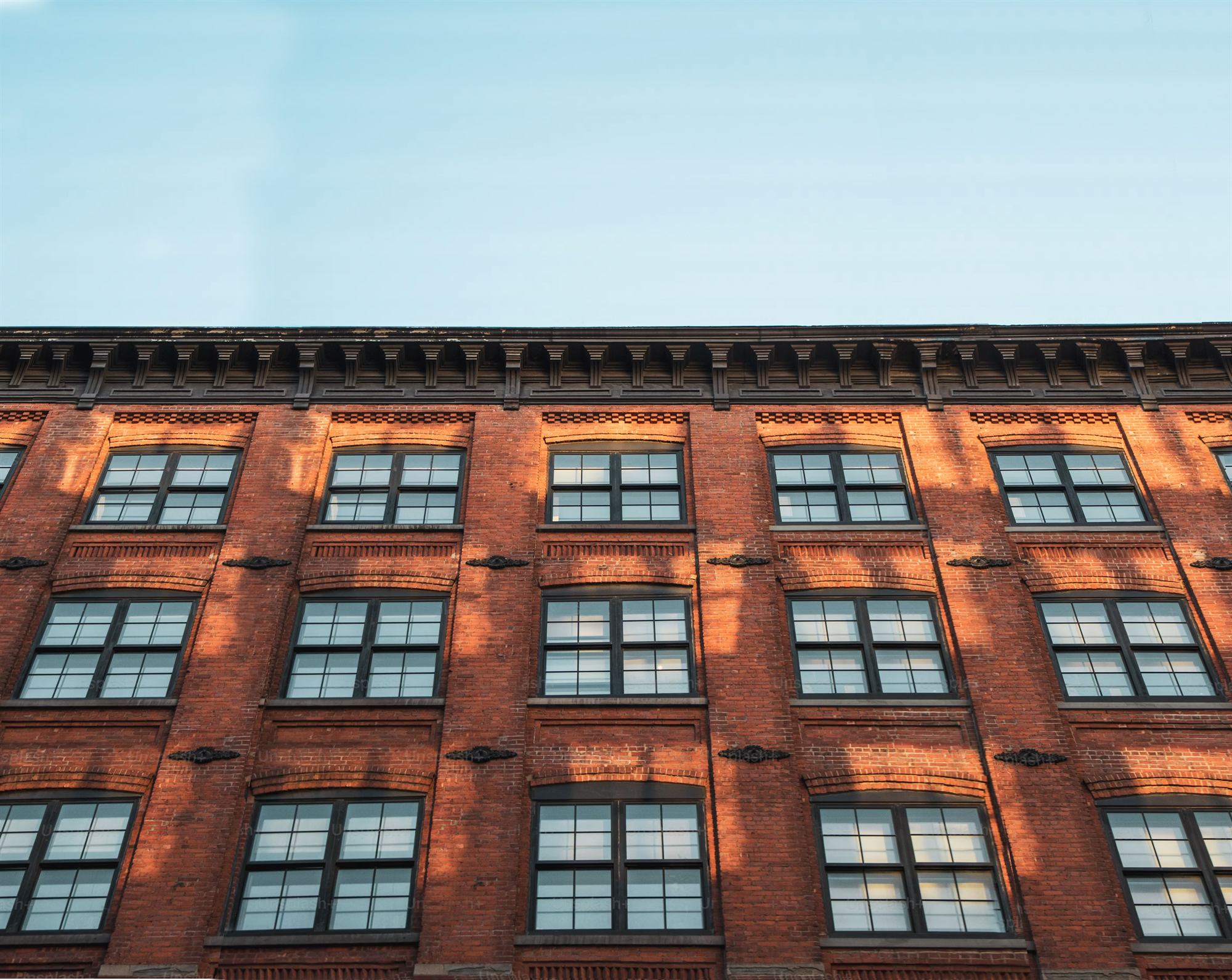 Historic brick building façade with a decorative cornice in warm light